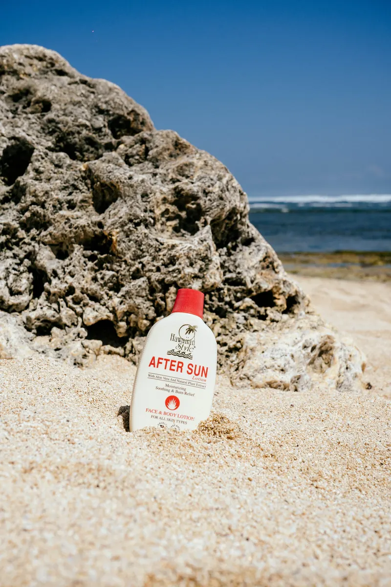 Hawaiian Style After Sun Lotion standing in the sand beside a beach rock