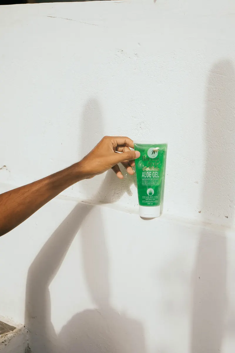 Hawaiian Style Aloe Gel held against a sunlit white wall with a long shadow
