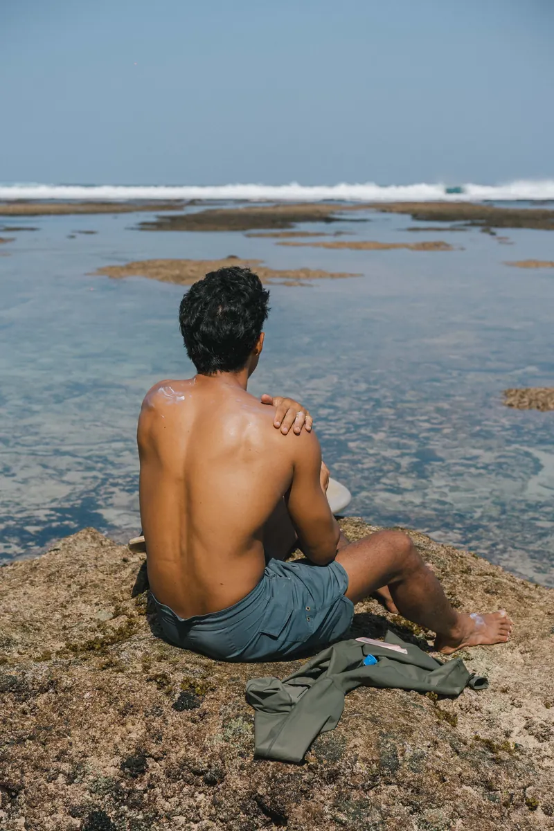 Hawaiian Style Sunblock SPF 50 being applied to a shoulder beside a tide pool