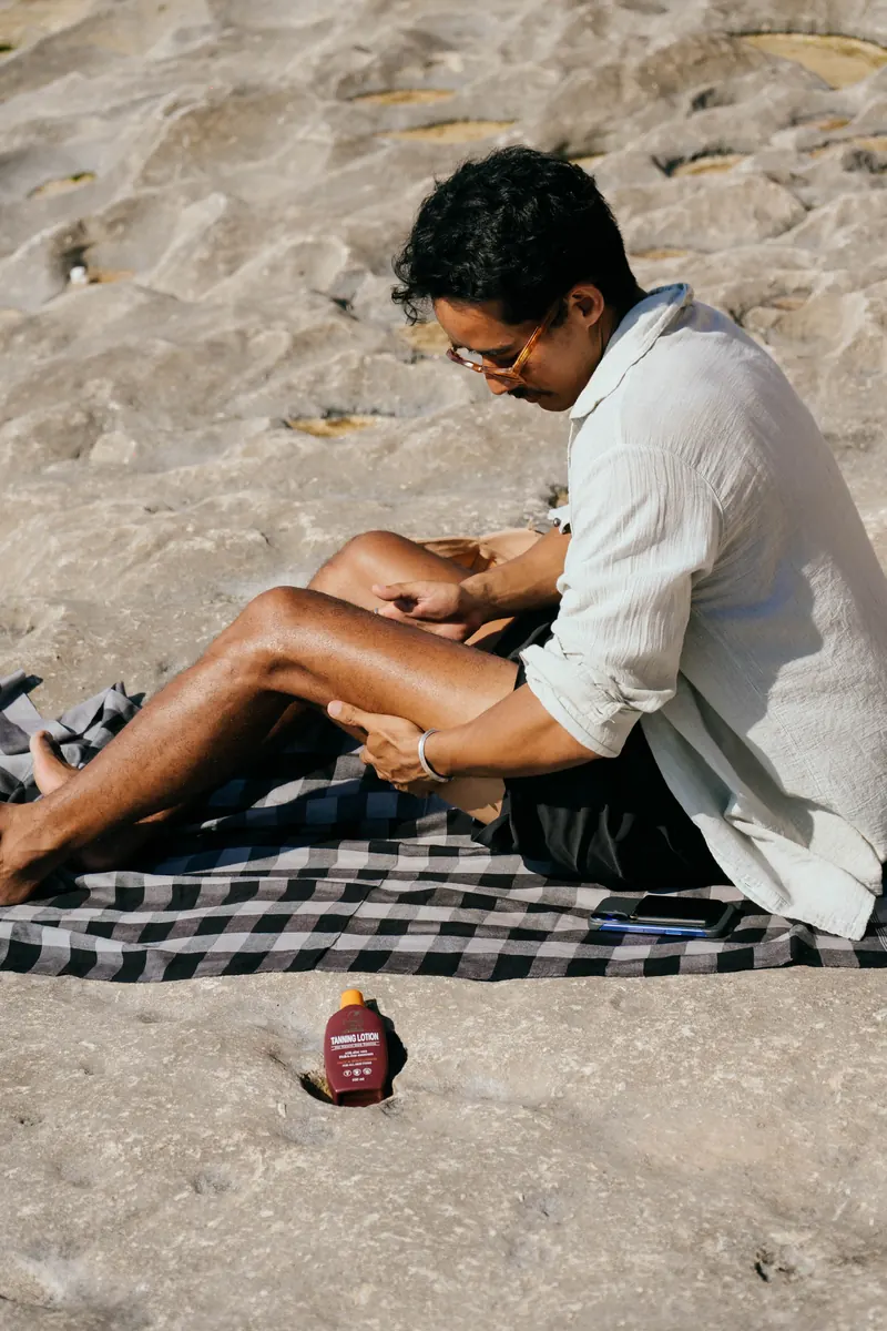 Hawaiian Style Coconut Tanning Oil pouring onto a rock beside a picnic blanket